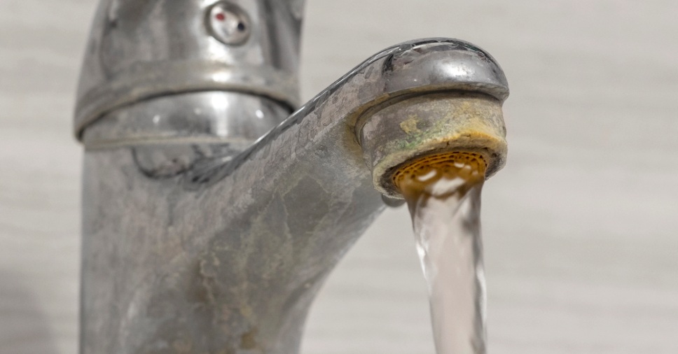 Torneira aberta, com sujidade no bico que são sinais de água dura